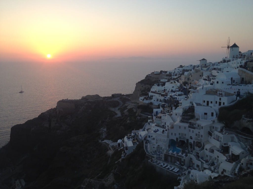 Whitewashed houses cascading on the top of a cliff in Oia, Santorini, at sunset