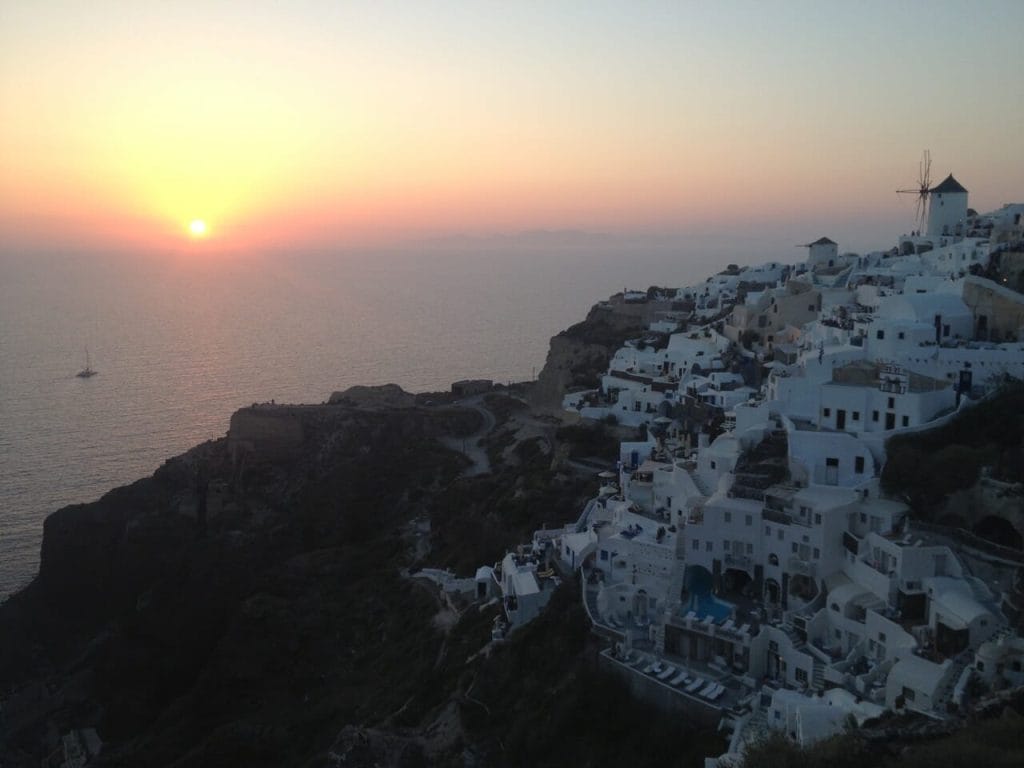 Casas encaladas en cascada sobre un acantilado en Oia, Santorini durante la puesta de sol