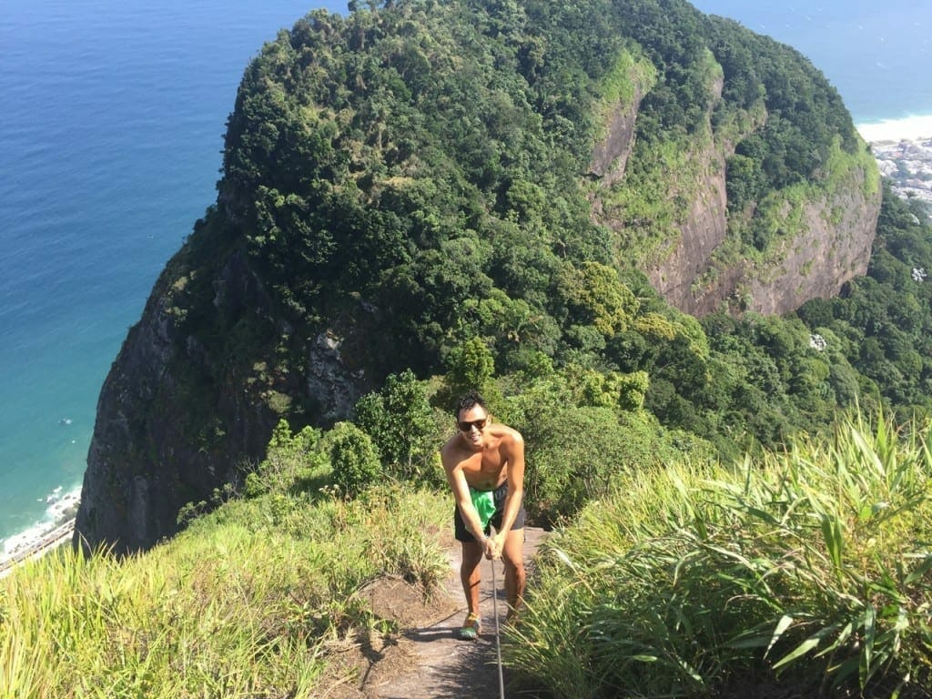 A man holding a cord and going down hill on Pedra da Gavea, Rio de Janeiro, Brazil