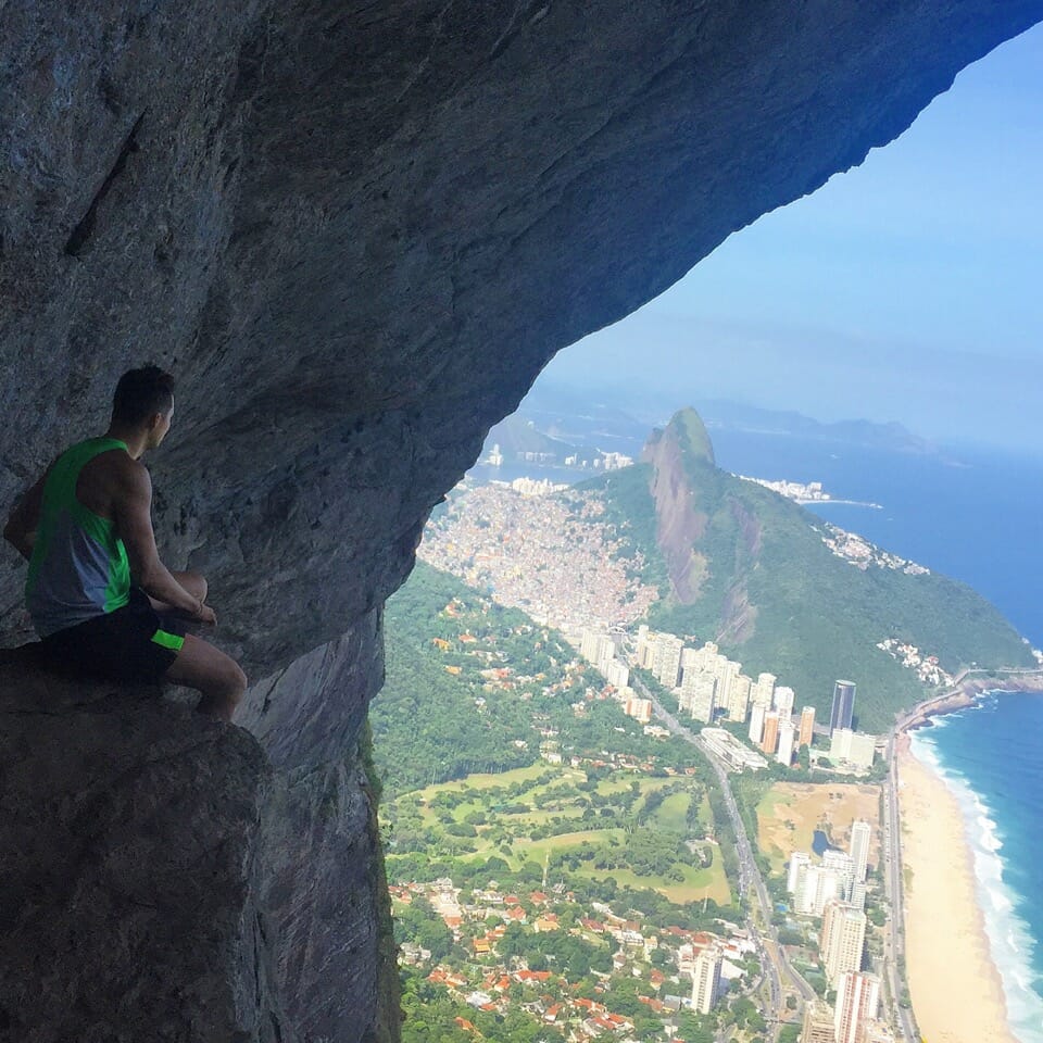 A man sitting down on a rock at 'Garganta do Céu' admiring the view of Rio de Janeiro from Pedra da Gavea