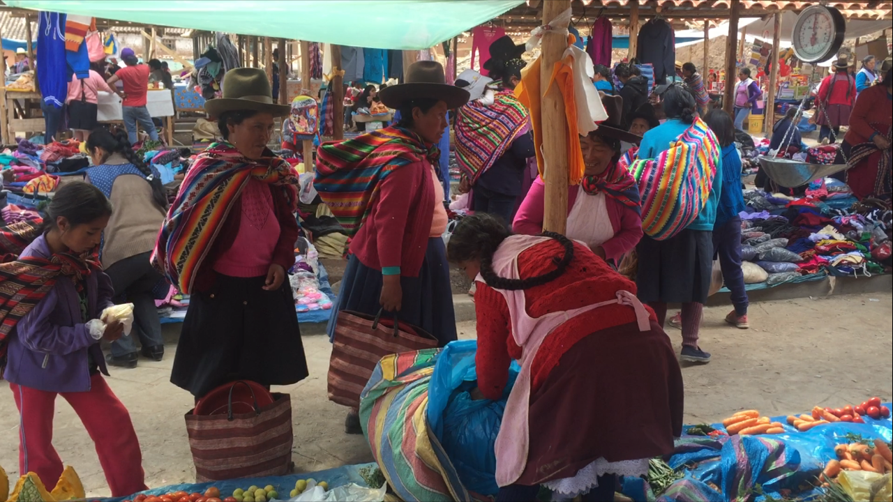 Mujeres que llevando víveres en la feria y vestindo ropa típica peruana