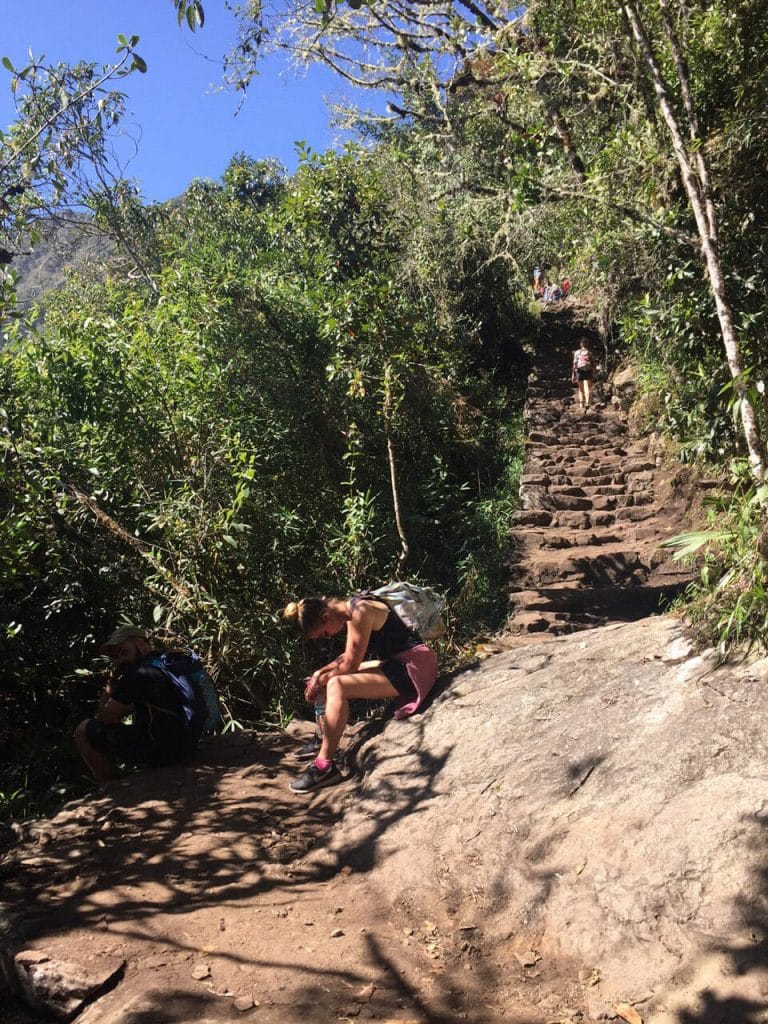 People resting and catching their breath on some steps at Machu Picchu Mountain, Peru