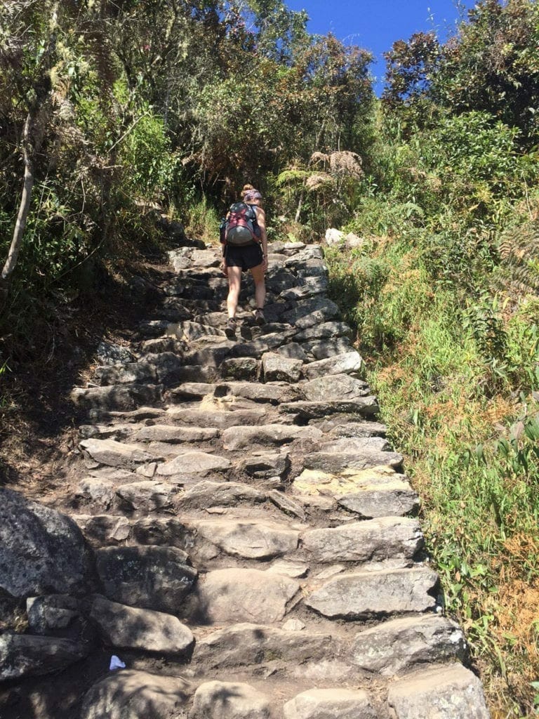 Una mujer subiendo los escalones del sendero de la montaña Machu Picchu, Perú