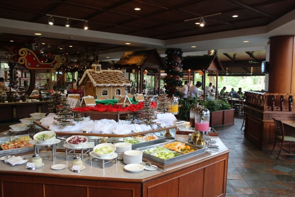 A buffet restaurant with a great variety of dishes, fresh fruits on white plates and juices