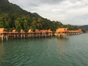 Overwater bungalows in Malay style backed up by mountains covered with luxurious vegetation