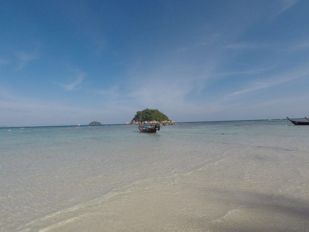 Sunrise beach at low tide, a boat on the water and a small island in the middle