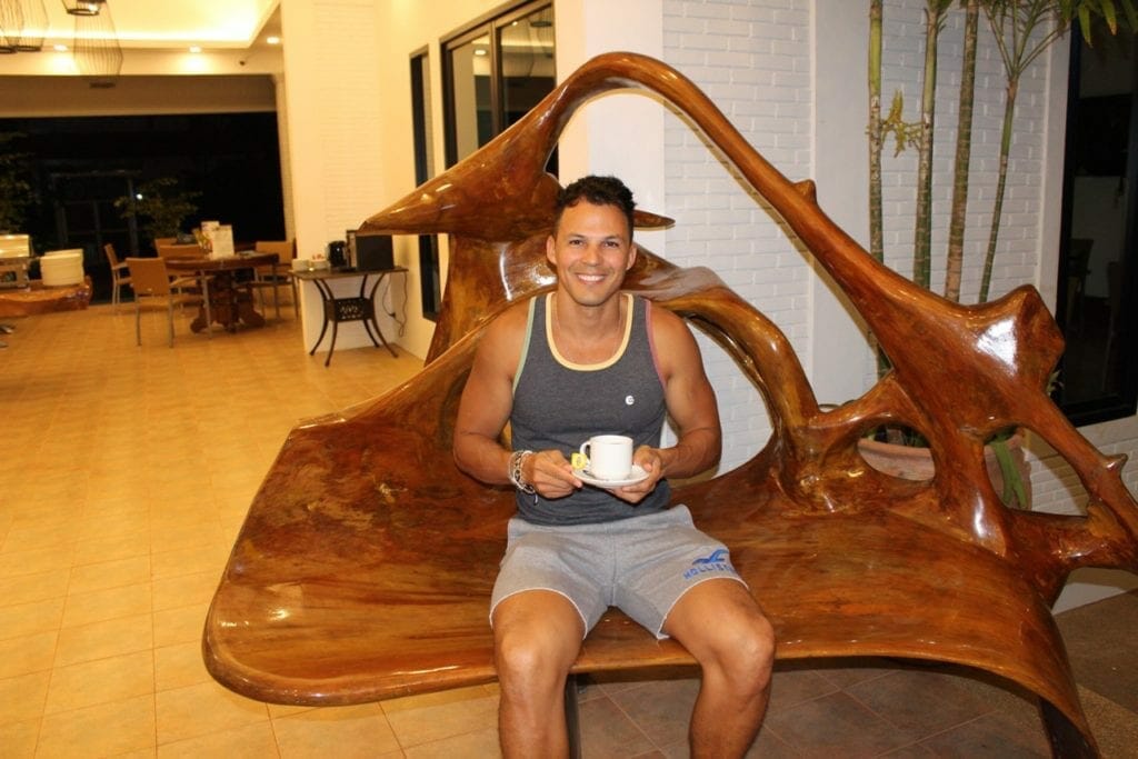 pericles rosa from 7 continents 1passport seating on a wood bench having a cup of tea at Alisea Pool Villas, Aonang, Thailand