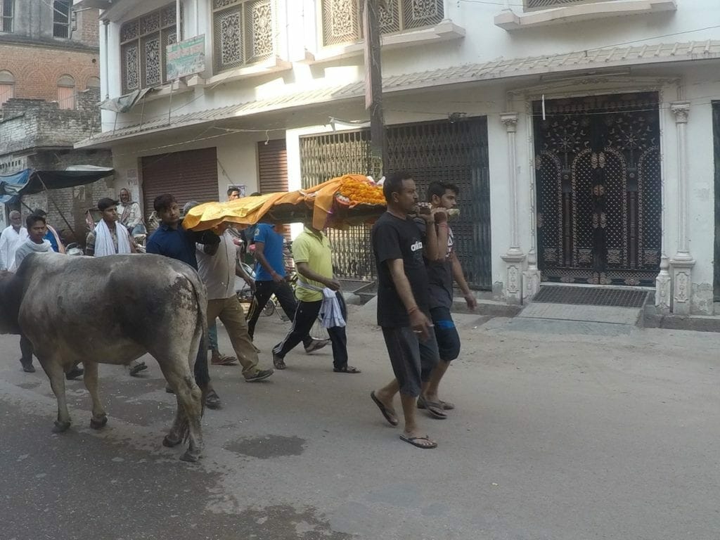 Pessoas carregando o corpo pelas ruas de Varanasi para ser cremado