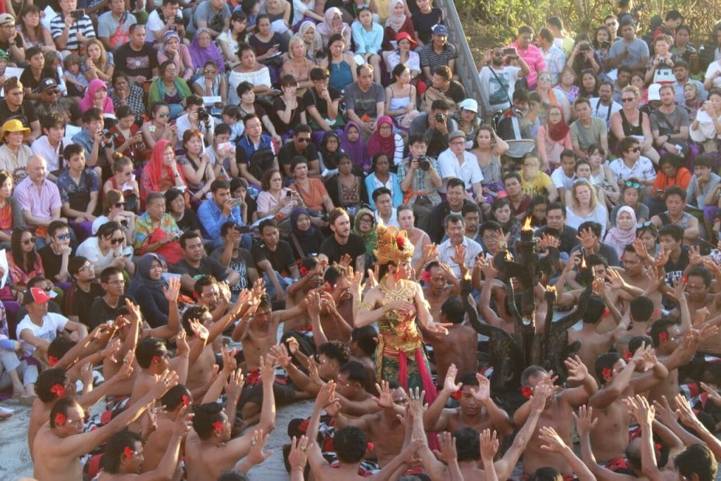 Espectadores assistindo à Dança Kecak em Bali, Indonésia, no Templo de Uluwatu durante o pôr do sol e os dançarinos no meio do palco