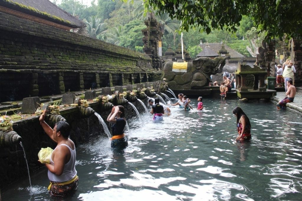 Pessoas na água, tomando banho nas fontes e orando no Templo da Água da Fonte Sagrada em Bali, Indonésia