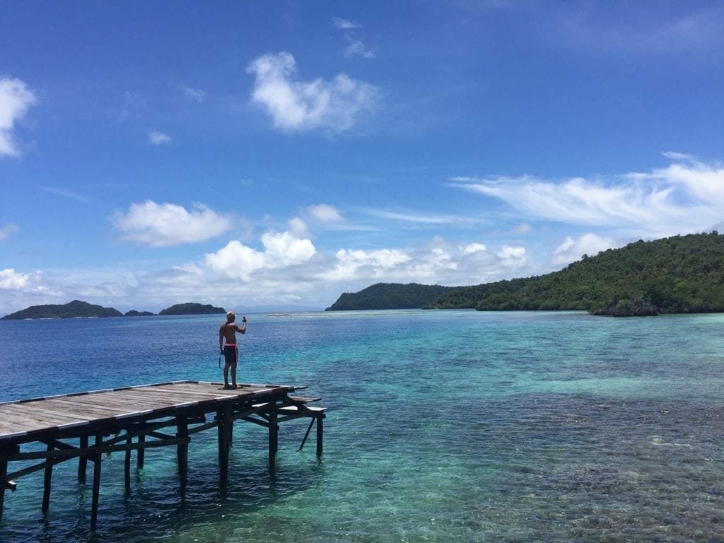 A man on a jetty taking pictures with his phone, Raja Ampat, Indonesia