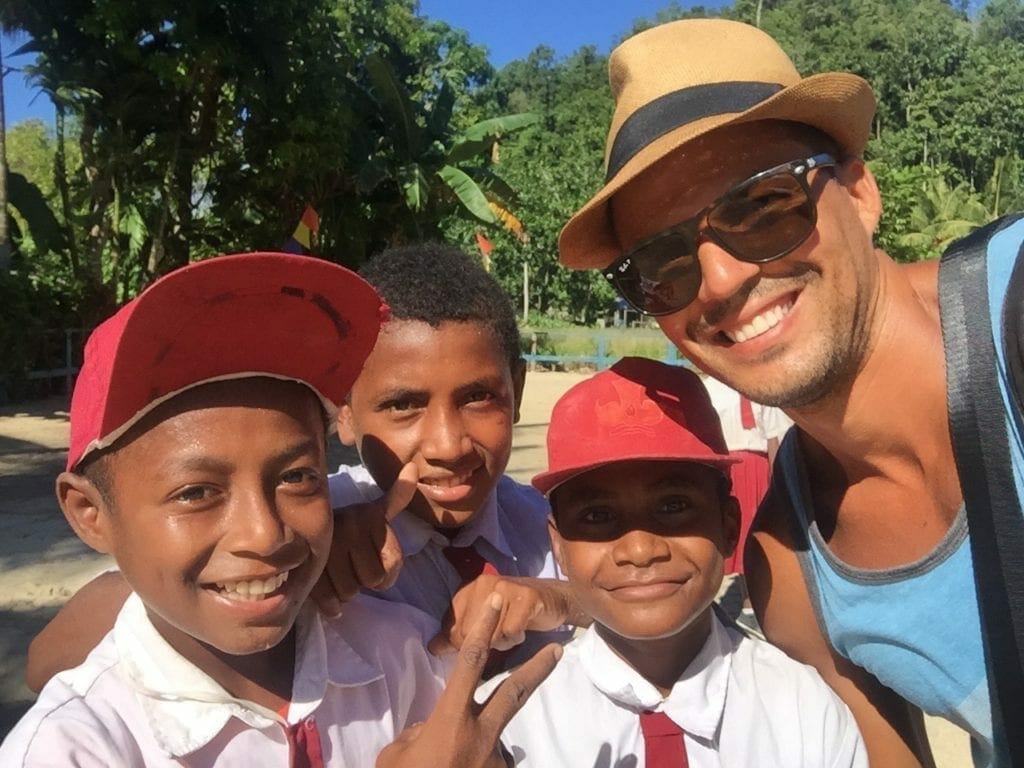 A man taking a selfie with three kids wearing school uniform in Raja Ampat, Indonesia