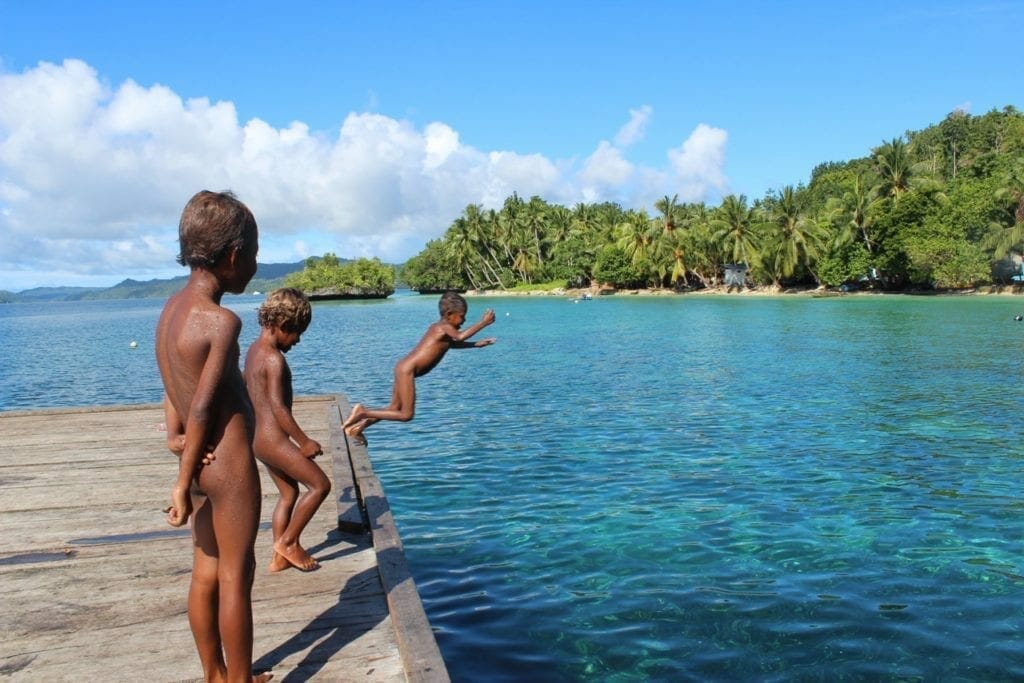 Three children from the jetty in the water, Raja Ampat, Indonesia