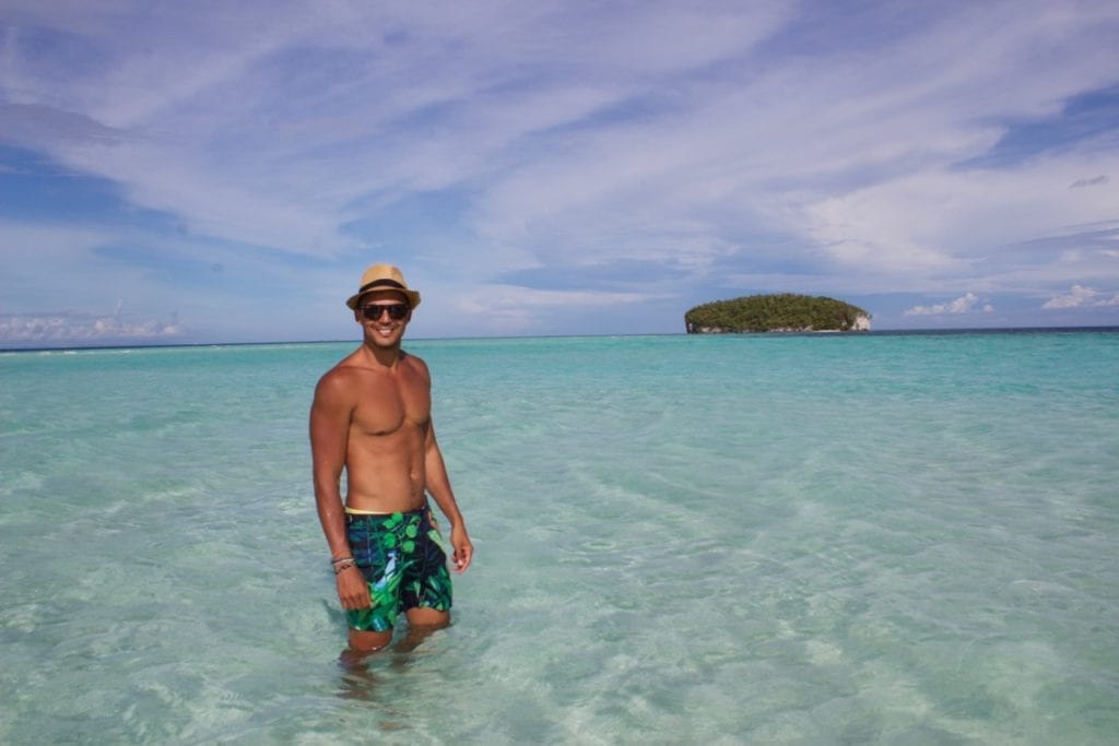 Pericles Rosa wearing a har, sunglasses and beach short posing for a picture at Pasir Timbul, Raja Ampat, Indonesia