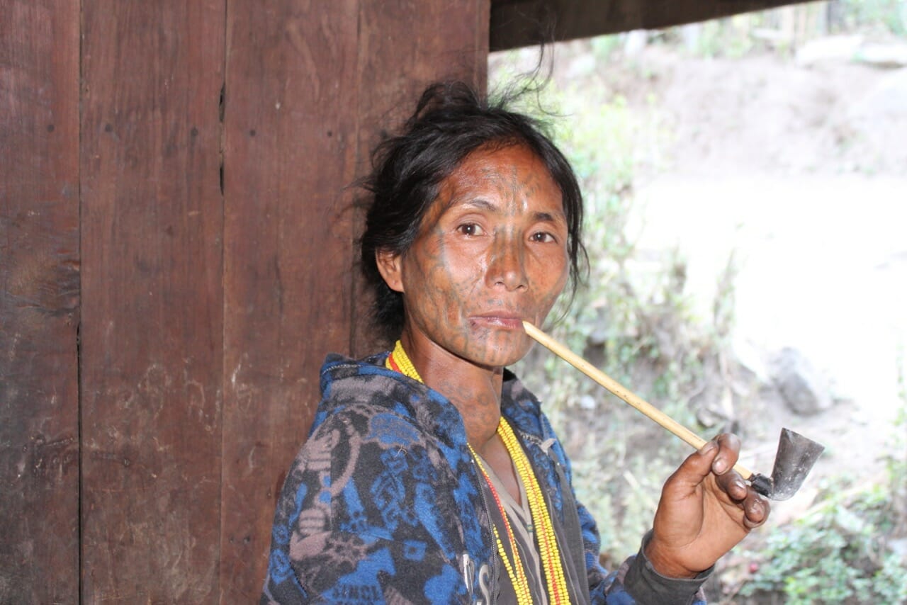 Una de las muy pocas mujeres con el rostro tatuado de Myanmar fumando tabaco en su pipa.