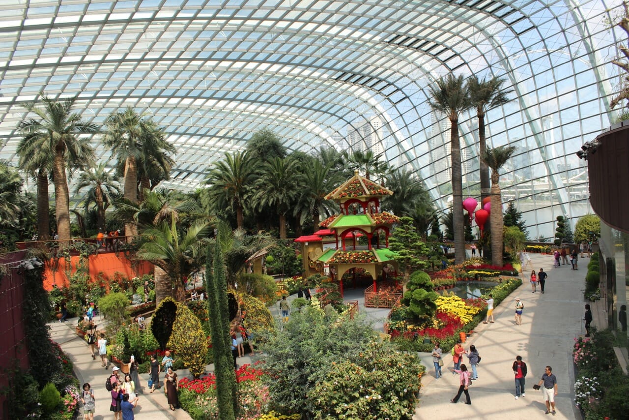 an immense huge climate-controlled conservatory with flowers, trees and people walking around