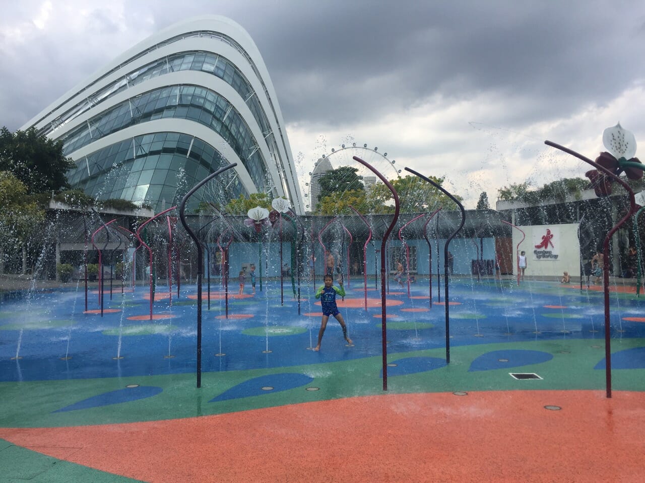 a children playing underneath some water fountains