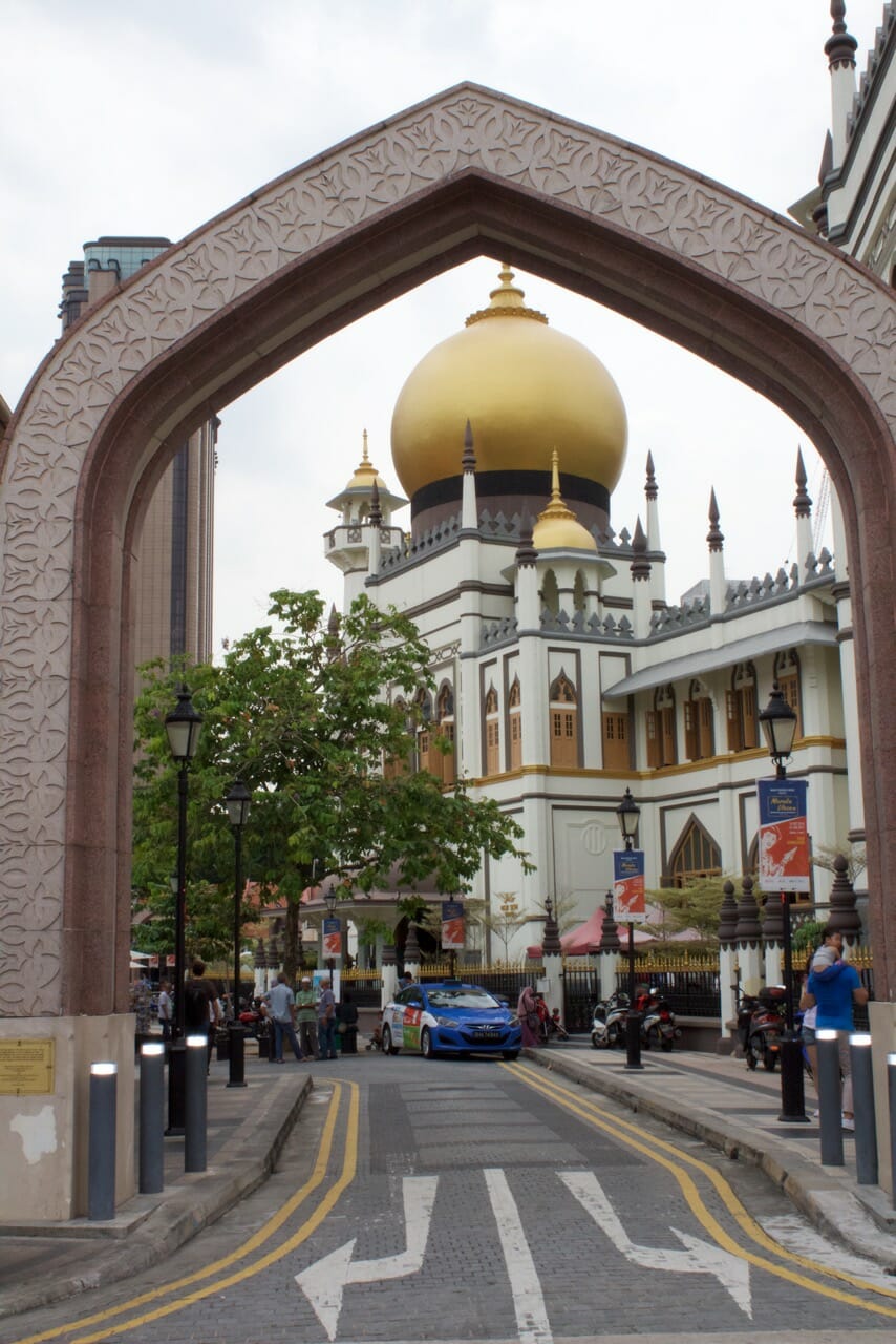 an street with an Arabic style arch with the Masjid Sultan Mosque in the background