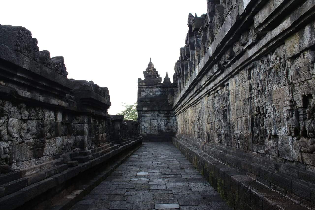 um dos corredores do templo de Borobudur com painéis esculpidos em relevo em ambos os lados
