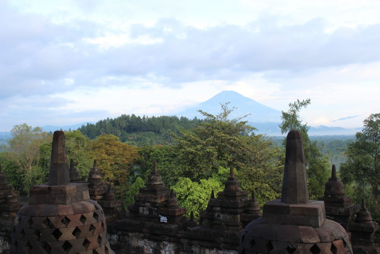 estupas, árboles y al fondo uno de los volcanes de la isla de Java