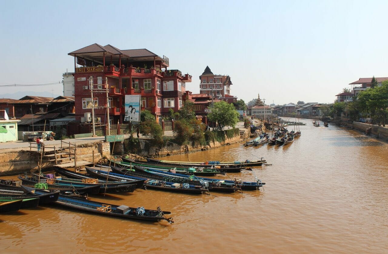 A canal that crosses Nyaung Shwe's main street with boat floats on the water and buildings on its banks