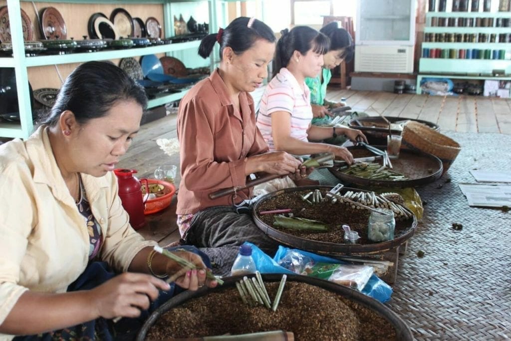 Quatro mulheres com cestas com tabaco enrolando charutos artesanais