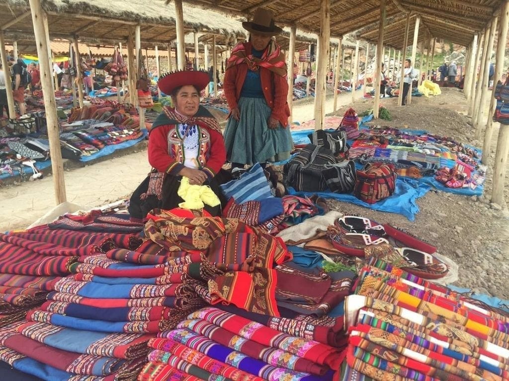 Una mujer vendendo textiles en el Mercado de Chinchero