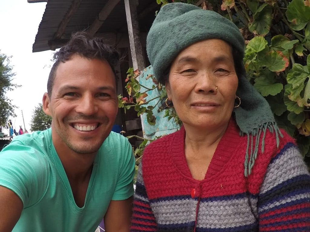 Pericles Rosa wearing a green t-shirt with a Nepalese woman wearing a green scarf on her head and a blue and red jumper at Place Hille Restaurant in Ulleri, Nepal.