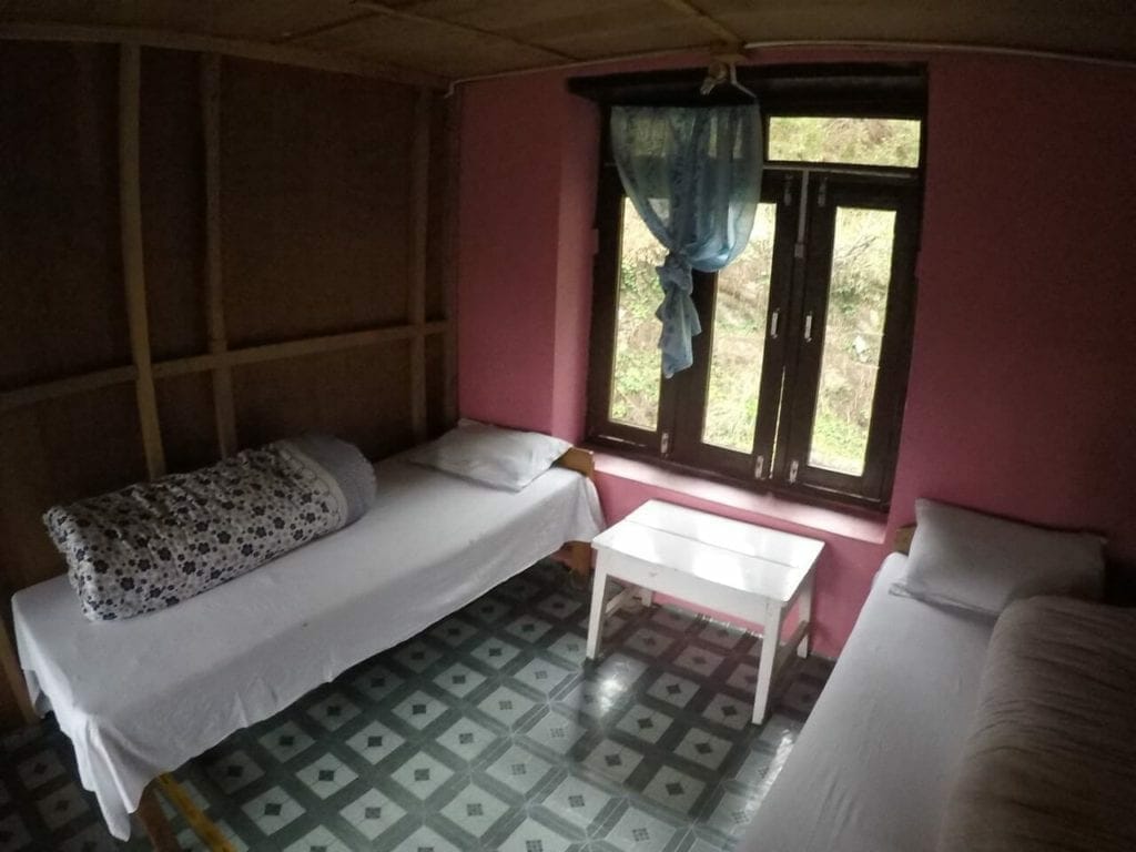 a room with two single beds and mosquito net between them at Tikhedhunga Guest House