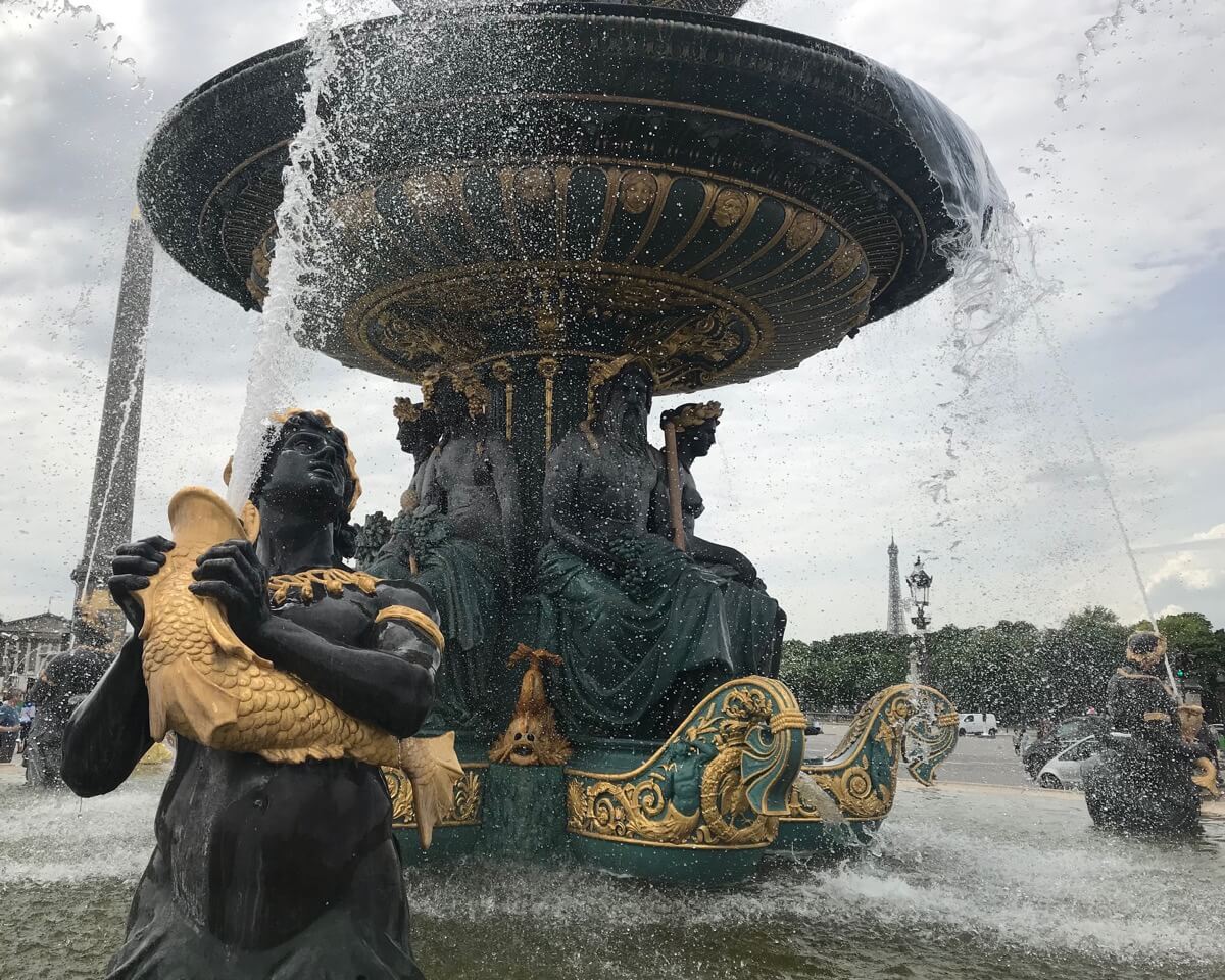 Una hermosa fuente en la Place de la Concorde, París, como estatuas negras con detalles dorados en la cabeza y jarras doradas con forma de pez