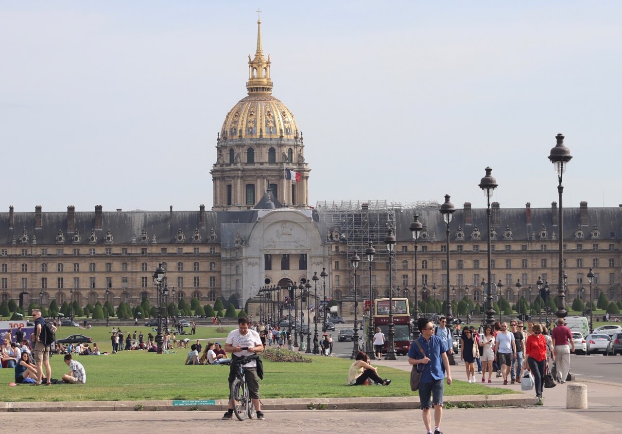 la gente caminando en la calle y ao fondo la bella fachada de Les Invalidés, París