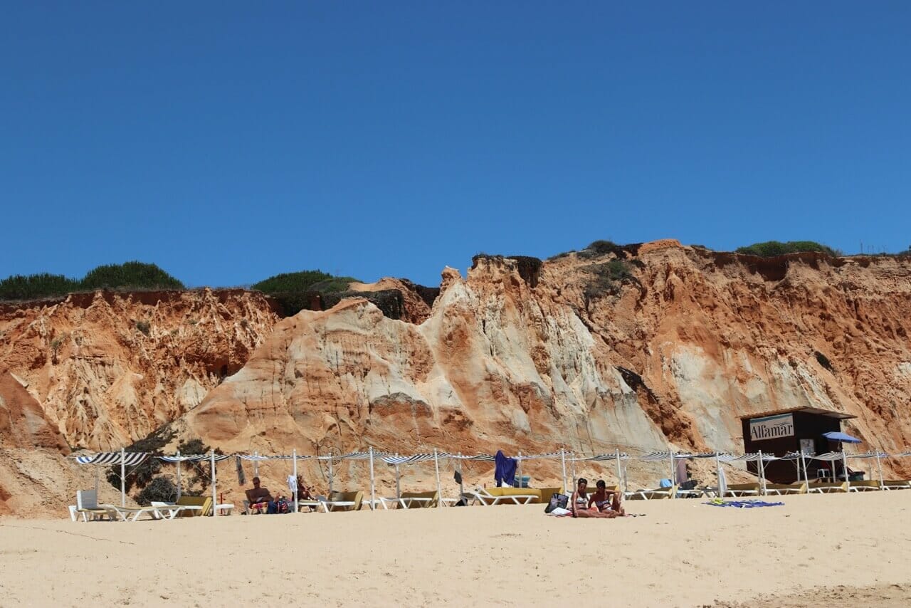 La gente a tomar sol en la Praia da Falésia, Albufeira, y al fundo los acantilados blancos y rojos que son muy típicos de esa playa