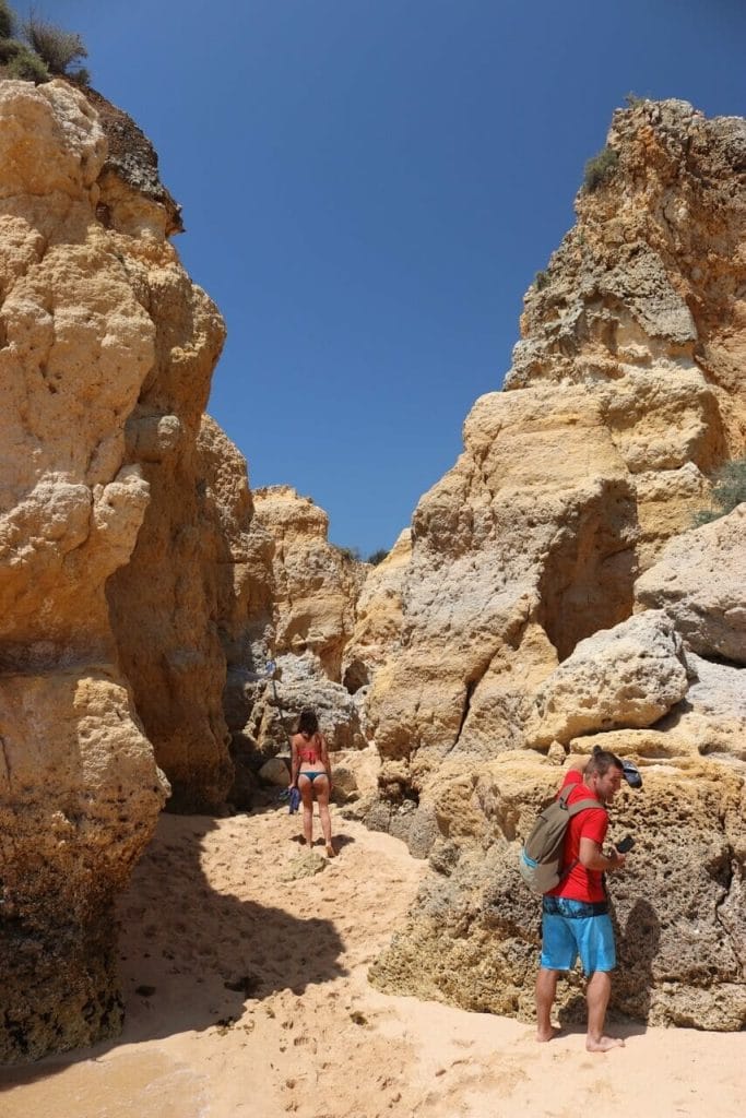 A man and a woman walking among the cliffs at Praia de São Rafael, Albufeira, Portugal