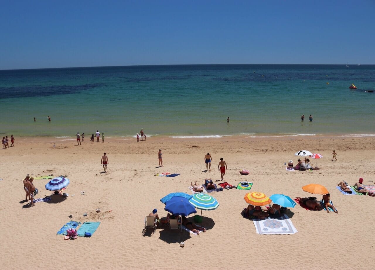 Sombreiros e pessoas na areia e no mar na Praia de Santa Eulália, Albufeira