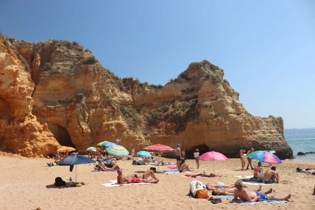 Parte da Praia do Pinhão, com guarda-sóis e gente tomando banho de sol e algumas falésias amarelas