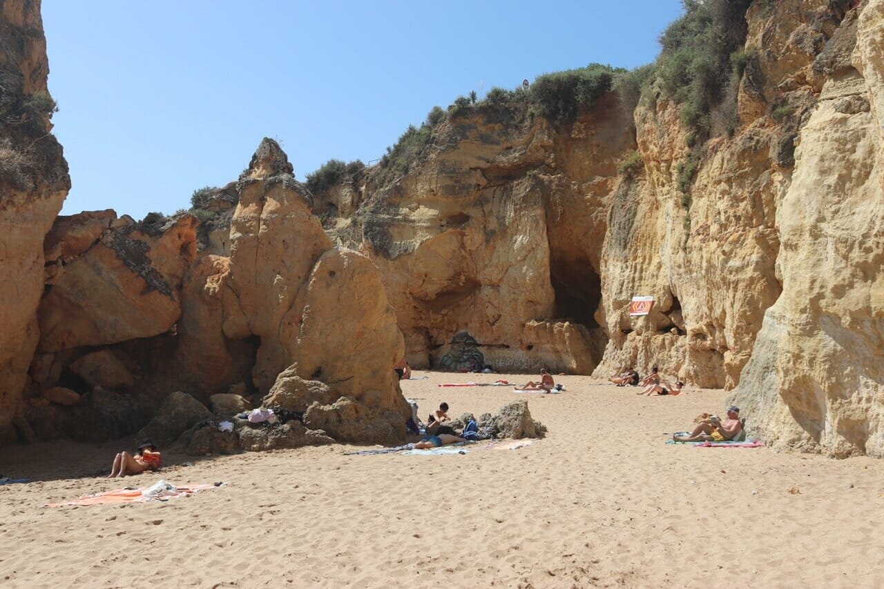 some people reading and sunbathing on Praia da Batata and some of its yellow cliffs