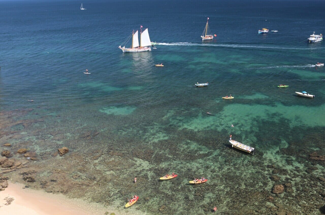barcos e caiaques, alguns recifes de coral e as águas azuis cristalinas da Praia Grande, Lagos, Portugal