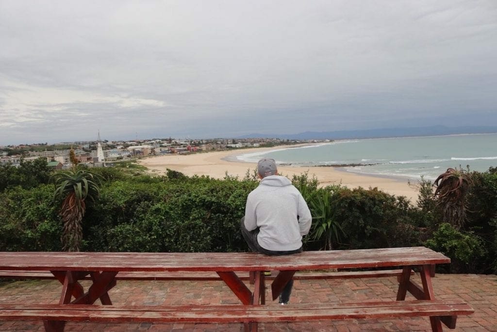 A man sitting on a beach overlooking the the sea at Island Vibe, Jeffreys Bay, South Africa