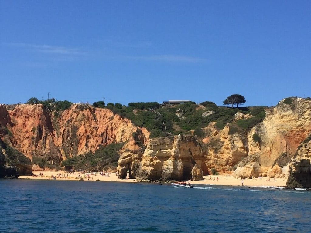 Vista desde el mar de Praia do Camilo, en Lagos, Portugal, y sus colosales acantilados de piedra caliza cubiertos de maleza