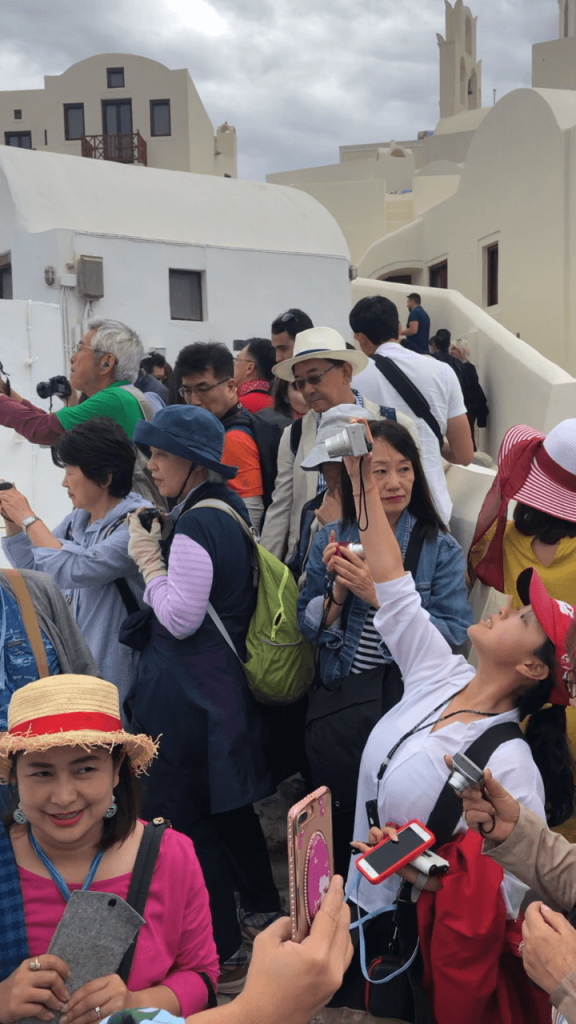 Muchos turistas un callejón en el pueblo de Oia, Santorini, Grécia
