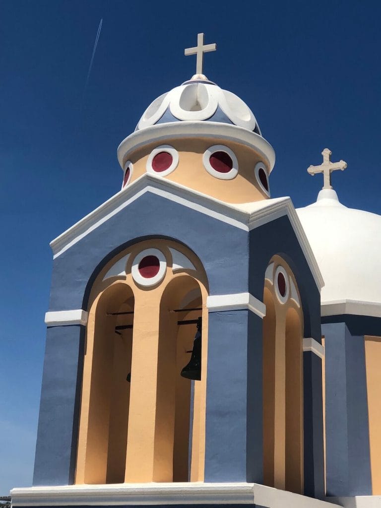 The picturesque white-domed Catholic Church of St. Stylianos, painted in blue, light orange with details in white and red