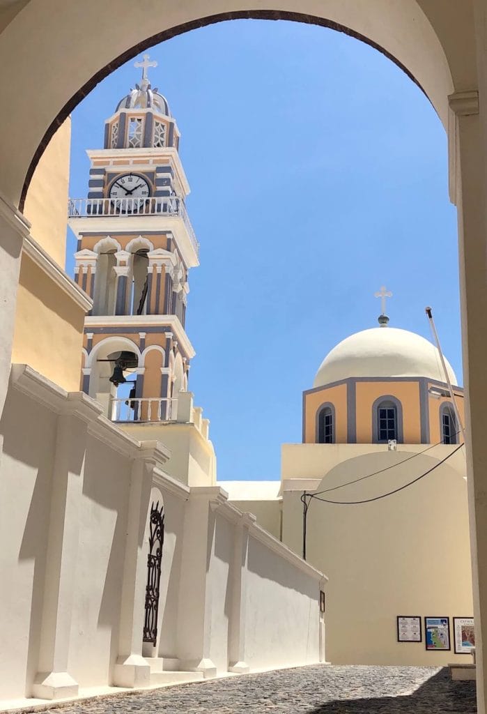 The beautiful bell tower and dome of Catholic Cathedral of Saint John the Baptist painted in pastel colours in Fira, Santorini