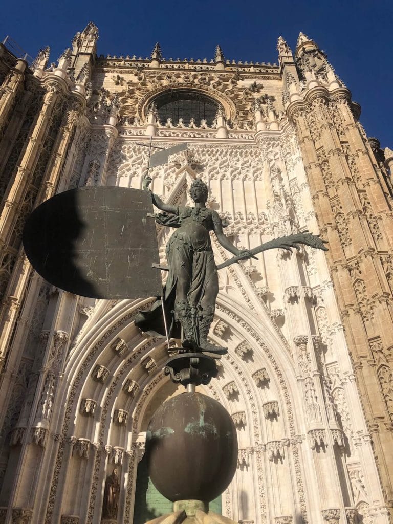 the facade of Seville cathedral with a the statue of the Giraldillo at the entrance