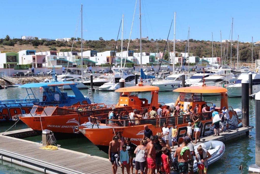 Numerosos barcos atracados en el puerto deportivo de Albufeira y personas saliendo de un barco turístico naranja