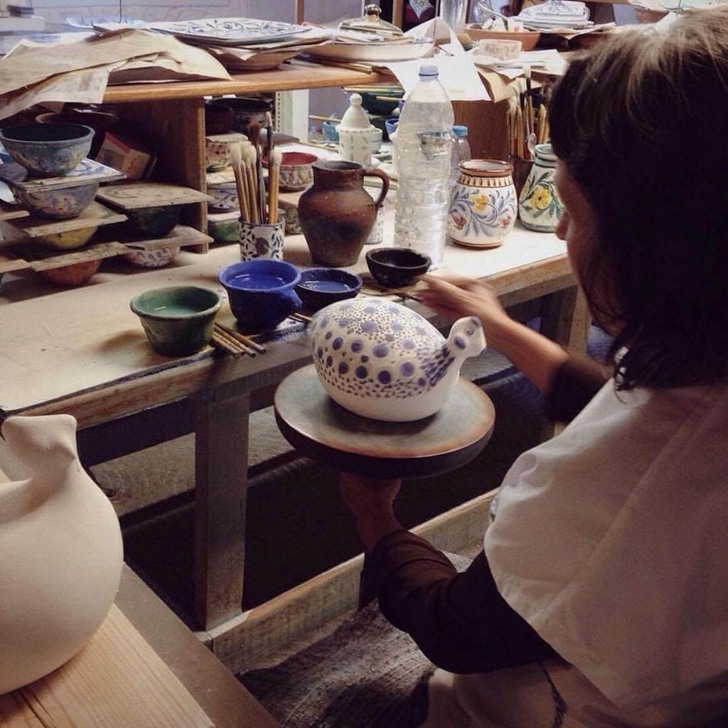An artisan hand-painting a decorative piece at Porches Pottery