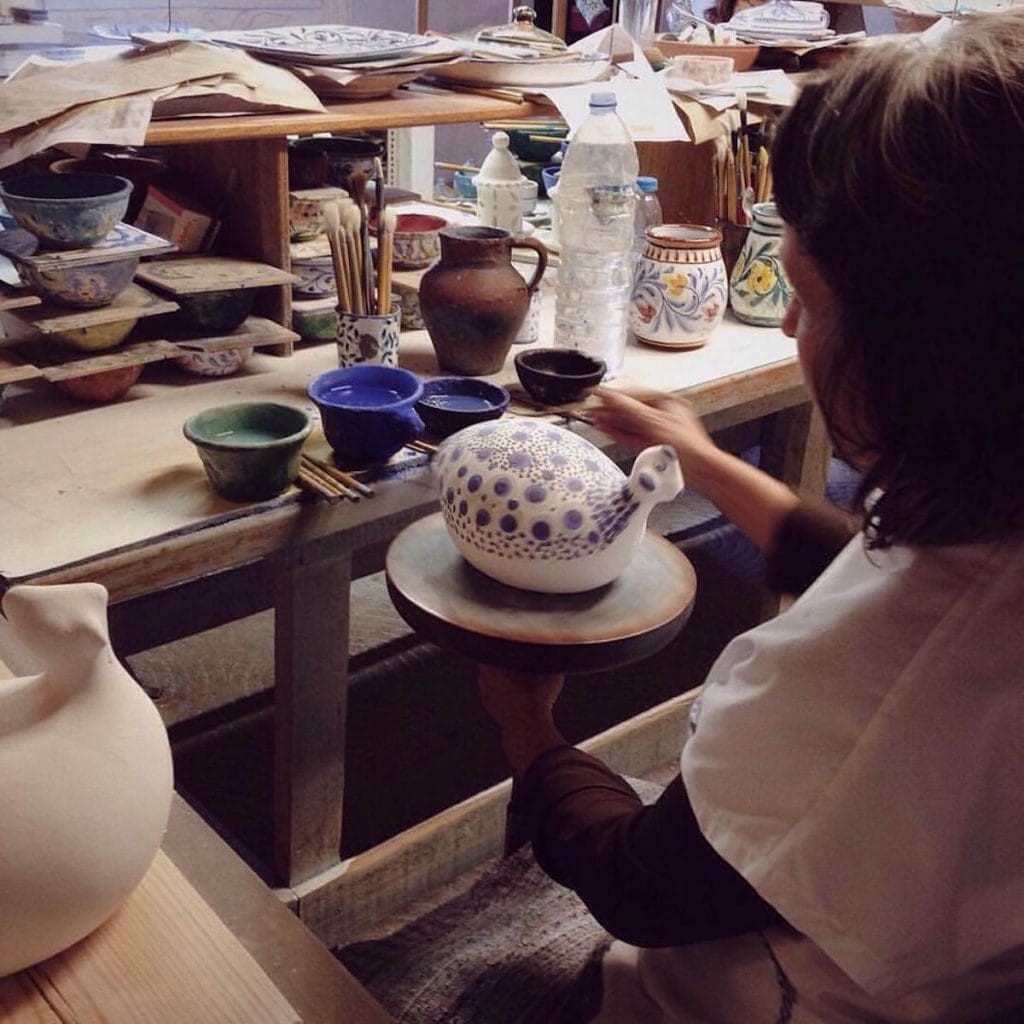 An artisan hand-painting a decorative piece at Porches Pottery