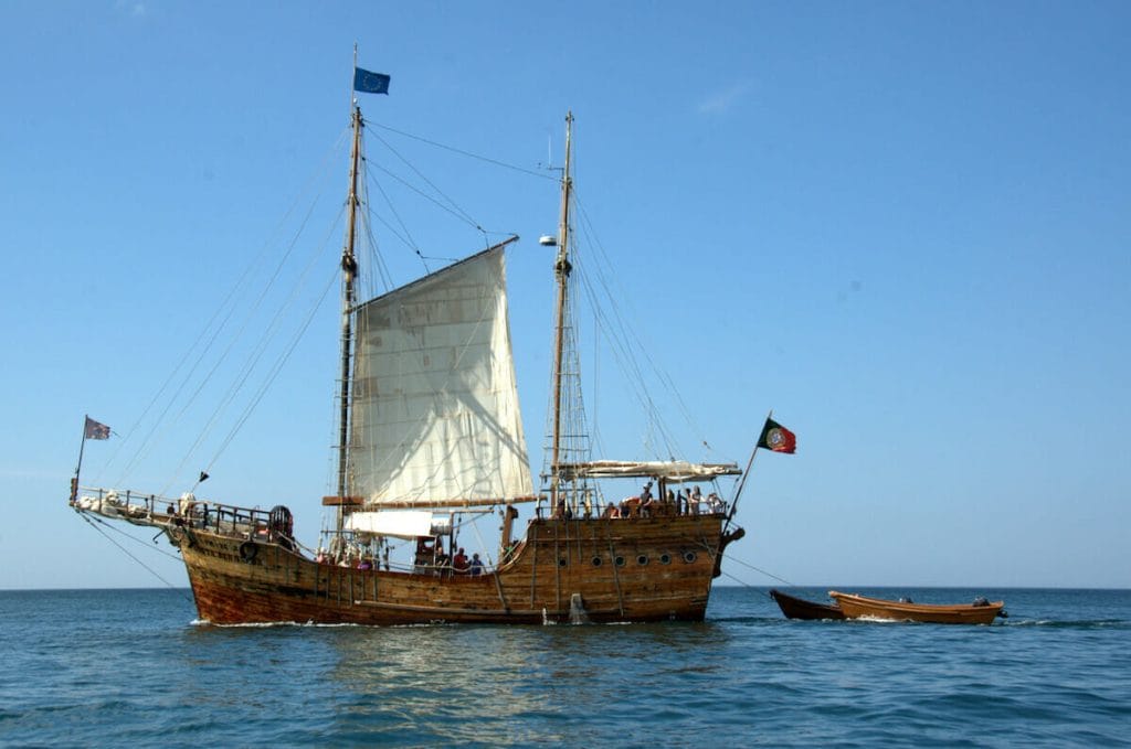 Um barco de madeira em estilo caravela velejando na costa do Algarve