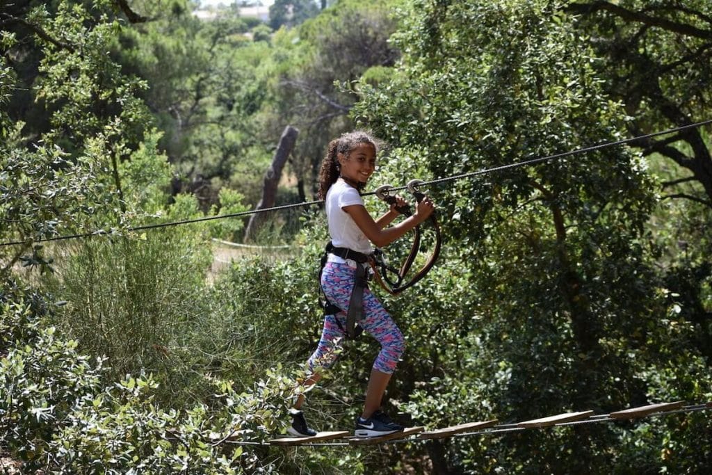 Um menina andando nas copas das árvores no Parque Aventura, Albufeira