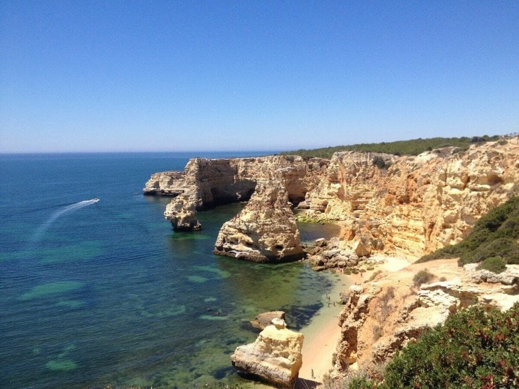 As falésias laranja-amareladas e as águas azuis da Praia da Marinha em Lagoa, Algarve, Portugal.