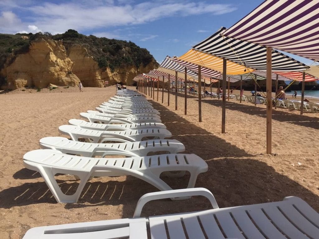 cadeiras brancas e guarda-sóis para alugar na Praia de Dona Ana, Lagos